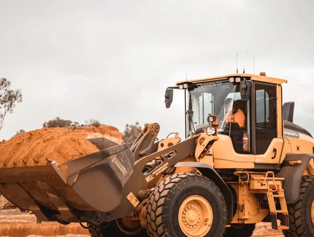 Buldozers ar vadītāju kabīnē un smiltīm pilnu traktora kausu